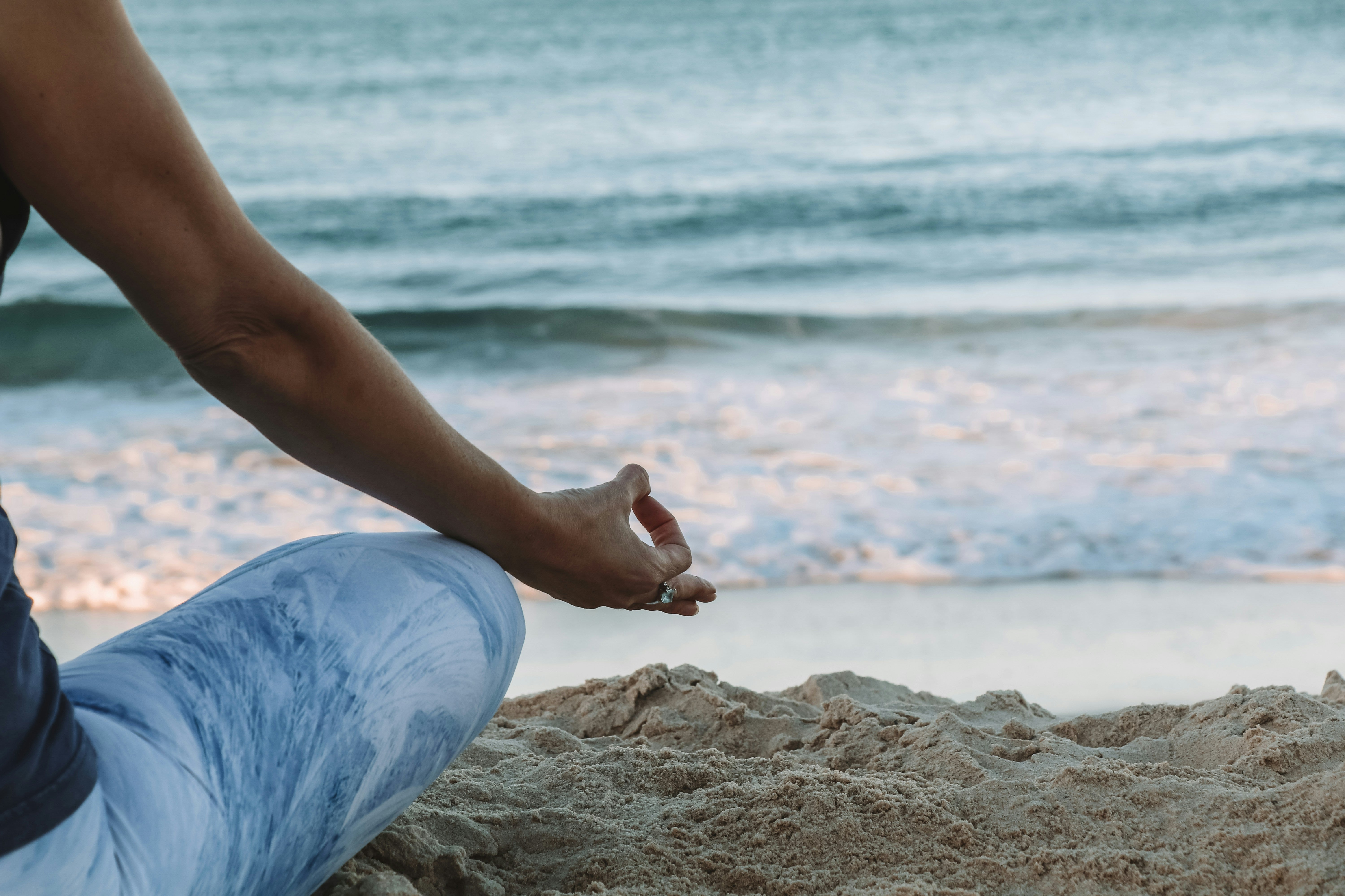 Femme en position de yoga devant une plage 